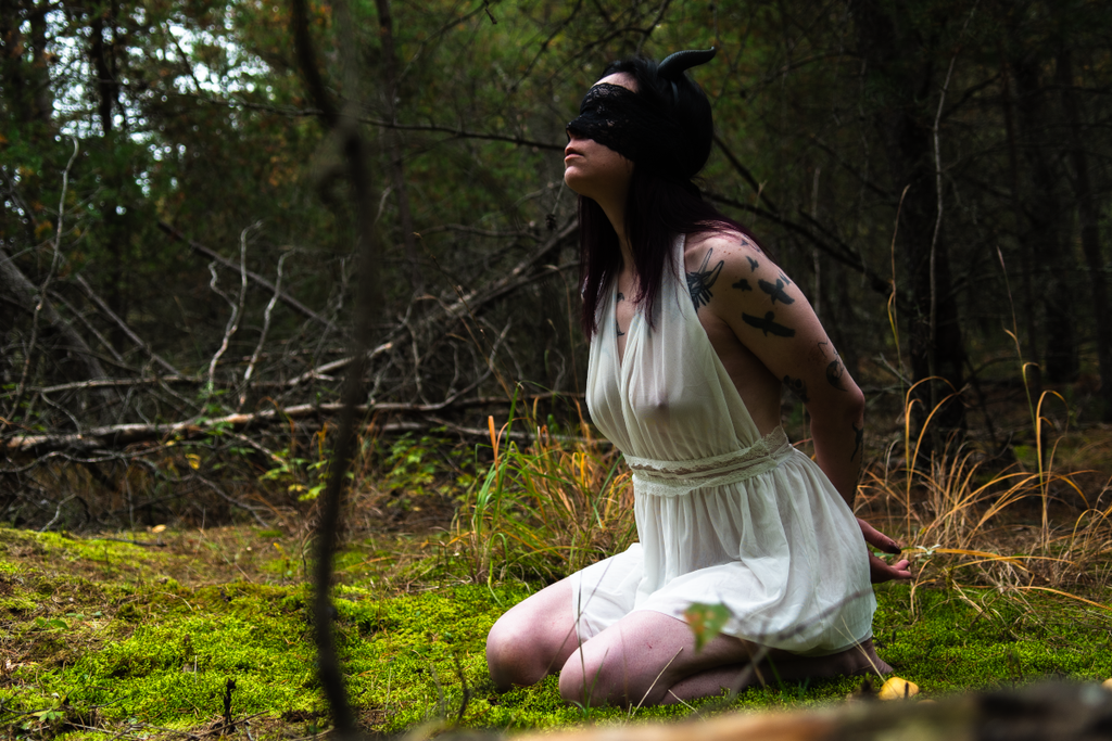 Horned girl in white gown in woods